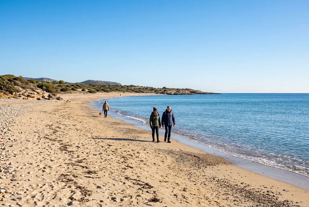 Quiet Mediterranean beach with walkers in jackets in January
